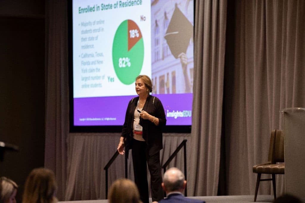 Carol Aslanian stands confidently at the podium, talking passionately about her latest report on Online College Students as a PowerPoint presentation flickers on the projection screen behind her.